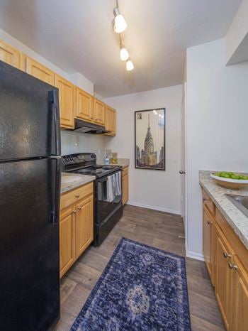 A kitchen with a black refrigerator freezer next to a stove top oven